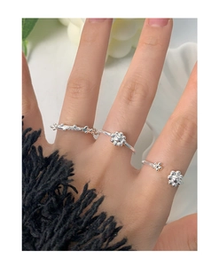 Detailed view of three-piece silver S925 floral stackable rings worn on a hand