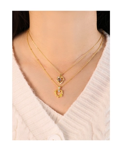 Collar de doble capa dorado con colgantes de cristal sobre un suéter blanco