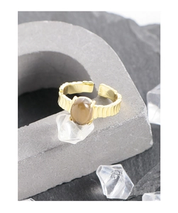 Detalle macro de anillo de plata S925 bañado en oro con gema marrón y textura estriada