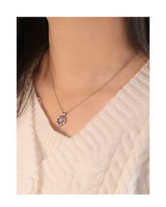 Detalle del collar de corazón en plata S925 con cristal marrón sobre jersey blanco