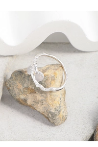 Detail view of S925 silver irregular twisted ring with dual agate stones on natural rock