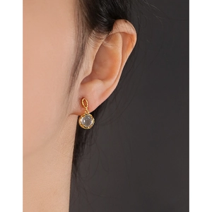 Elegant gold-trimmed round tea quartz earrings on model with minimalist textured finish