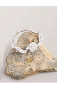 Gros plan de la bague en argent S925 ondulée avec agate blanche sur roche brute