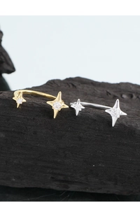 Macro shot of gold and silver starburst rings with zircons on a textured dark base