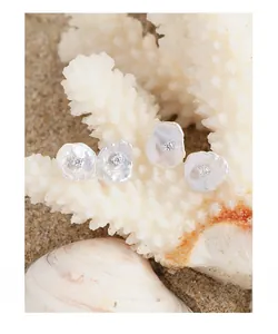 Macro detail of natural baroque pearl earrings with square zircons on white coral