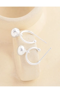 Detail of silver S925 earrings with spherical charms on a ceramic mug edge