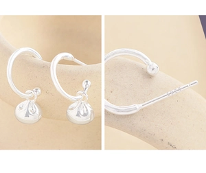 Macro shot of S925 sterling silver hallmark and lucky bag drop earrings on ceramic
