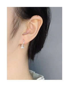 Close-up of a minimalist silver fortune bag earring worn on a model's earlobe