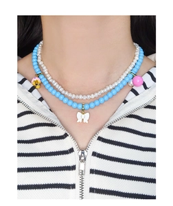 Gros plan d'un collier à double rang de perles bleues avec un pendentif nœud blanc