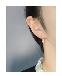 Detailed view of polished solid silver lucky bag earrings worn on woman's earlobe