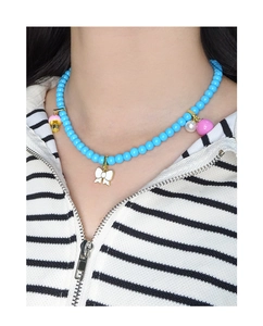 Gros plan d'un collier de perles bleues avec pendentif nœud porté par un mannequin