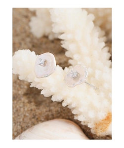 Detailed view of S925 silver baroque pearl earrings with zircon on a beach background