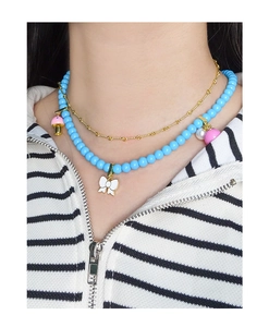 Détail d'un collier multicouche avec perles bleu ciel et pendentif nœud blanc femme