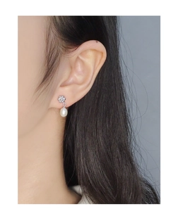 Gros plan d'une boucle d'oreille fleur en argent s925 avec pendentif perle d'eau douce