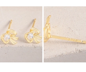 Macro view of S925 hallmark on gold bow earrings featuring a sparkling zircon center