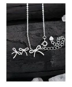 Vue macro d'un ensemble collier et boucles d'oreilles nœud en argent S925 sur bois