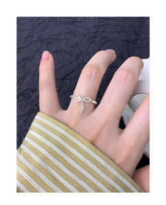 Gros plan d'une bague nœud en argent sur un doigt avec un fond de manche rayée