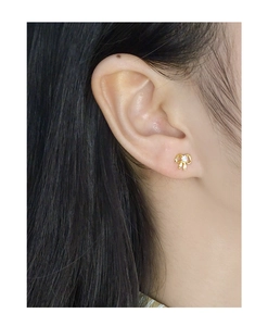 Close-up of a delicate gold bow stud earring with a sparkling zircon on an earlobe