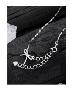 Détail du collier noeud en argent S925 avec pendentif coeur sur fond de bois sombre