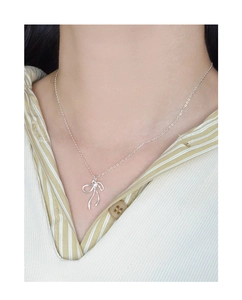 Collier avec pendentif nœud argenté porté par un mannequin en chemise à rayures
