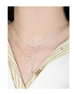 Détail du collier triple rang en argent S925 avec pendentifs nœud et fleur élégants