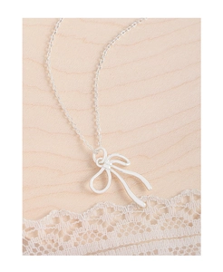 Gros plan détaillé du collier avec pendentif nœud en argent S925 sur dentelle et bois clair
