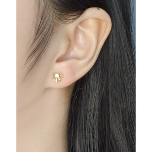 Elegant gold bow earrings with zircon center displayed on model ear in a refined style
