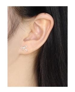 Gros plan d'une boucle d'oreille nœud en argent portée à l'oreille au fini poli