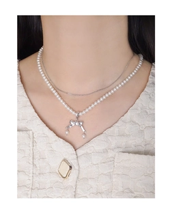 Dettaglio di una collana a due strati con ciondolo a fiocco d'argento e perle fini