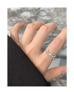 Detailed close-up of a silver hollow bow ring made of S925 sterling silver on finger