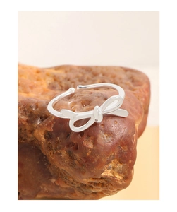 Detail of silver bow tie ring with polished finish on a textured reddish stone