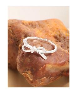 Macro detail of a 925 sterling silver bow knot open ring on a natural rock background
