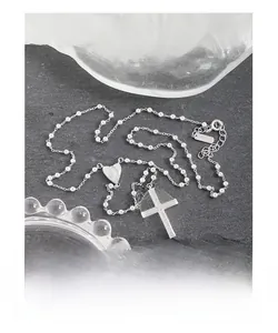 Gros plan sur collier perlé en argent S925 avec pendentif croix et icône de cœur