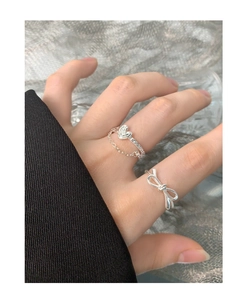 Close-up of S925 sterling silver bow-knot and heart chain rings worn on a hand