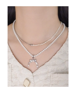 Dettaglio della collana a fiocco in argento S925 con perle eleganti sul collo della modella