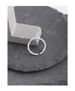 Détail de la bague ouverte en argent S925 avec petites perles sur support en pierre
