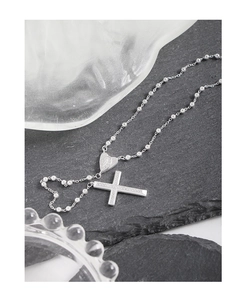 Détail macro du pendentif croix en argent S925 serti de zircons avec gravure de cœur