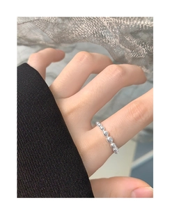 Macro shot of minimalist high-polish silver beaded ring on finger with sleek metal balls