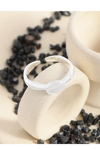 Macro detail of irregular lava texture and polished oval silver ring on black stones