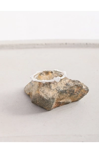 Macro shot of silver S925 heart-shaped ring resting on a natural stone background