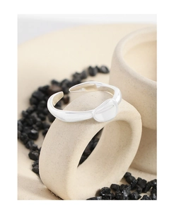 Macro detail of silver minimalist lava style ring on white ceramic prop with black stones