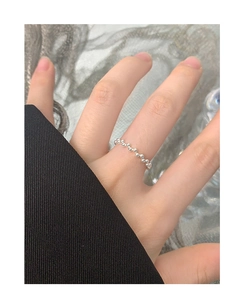 Macro detail of a minimalist S925 sterling silver beaded ring worn on a finger