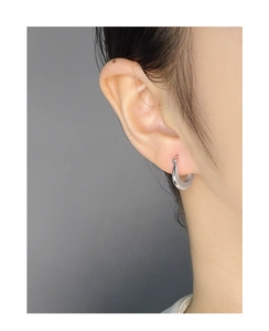 Close-up of polished S925 sterling silver U-shaped hoop earrings on a model