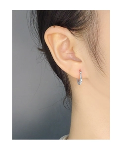 Close-up of minimalist U-shape silver earring worn by model showing polished metal finish
