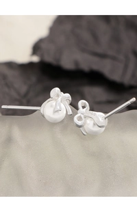 Macro detail of S925 sterling silver bow earrings with elegant white pearl accents