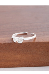 Detail of S925 sterling silver bow ring with small heart on a dark wood surface