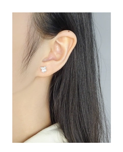 Detail of S925 silver bow stud earrings with white pearl on model's ear