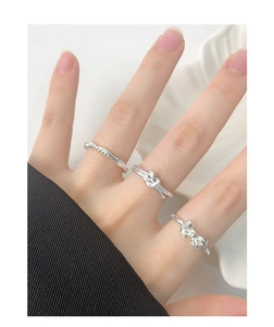 Detailed view of silver bow and knot rings stacked on a model in a minimalist style