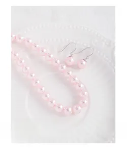 Macro shot of pink pearl necklace and matching earrings on a white vintage plate