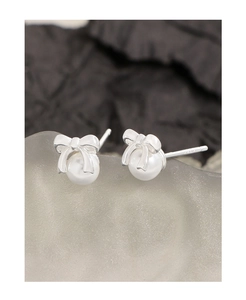 Macro view of S925 silver bow stud earrings with glossy white pearl details